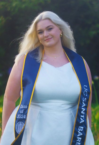 graduation photo of grace in a white dress and blue ucsb sash